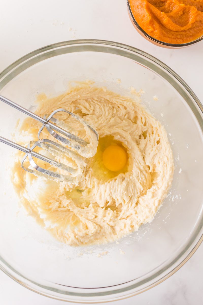 A mixing bowl filled with creamy batter and eggs in which egg beaters will be blending into the batter - Hostess At Heart