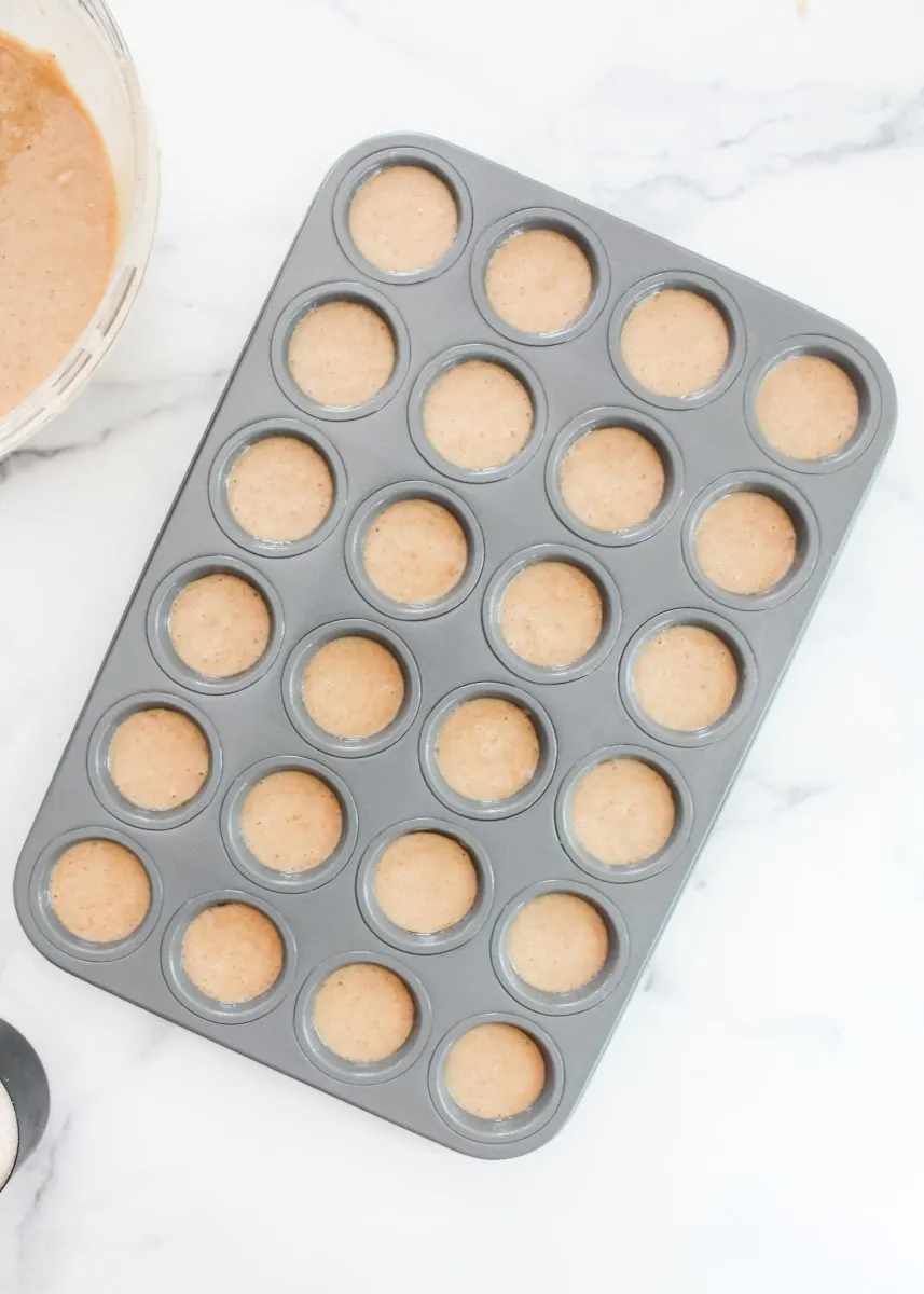 Top-down view of a mini muffin pan filled with batter. Hostess At Heart