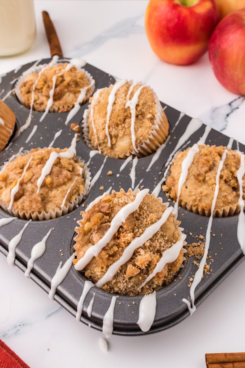 Glazed Apple Muffins topped with Crumble in a muffin tin. Hostess At Heart