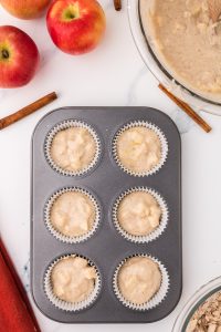 A muffin tin filled 2/3 full with apple muffin batter. Hostess At Heart