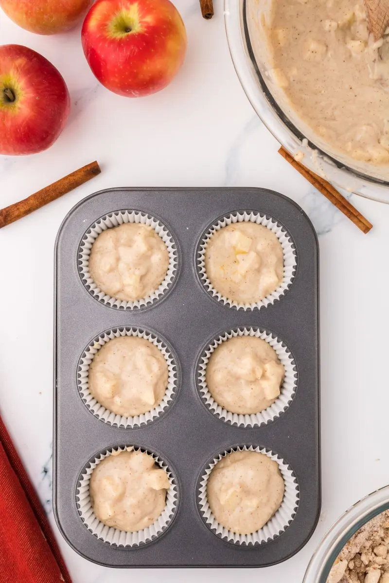 A muffin tin filled 2/3 full with apple muffin batter. Hostess At Heart