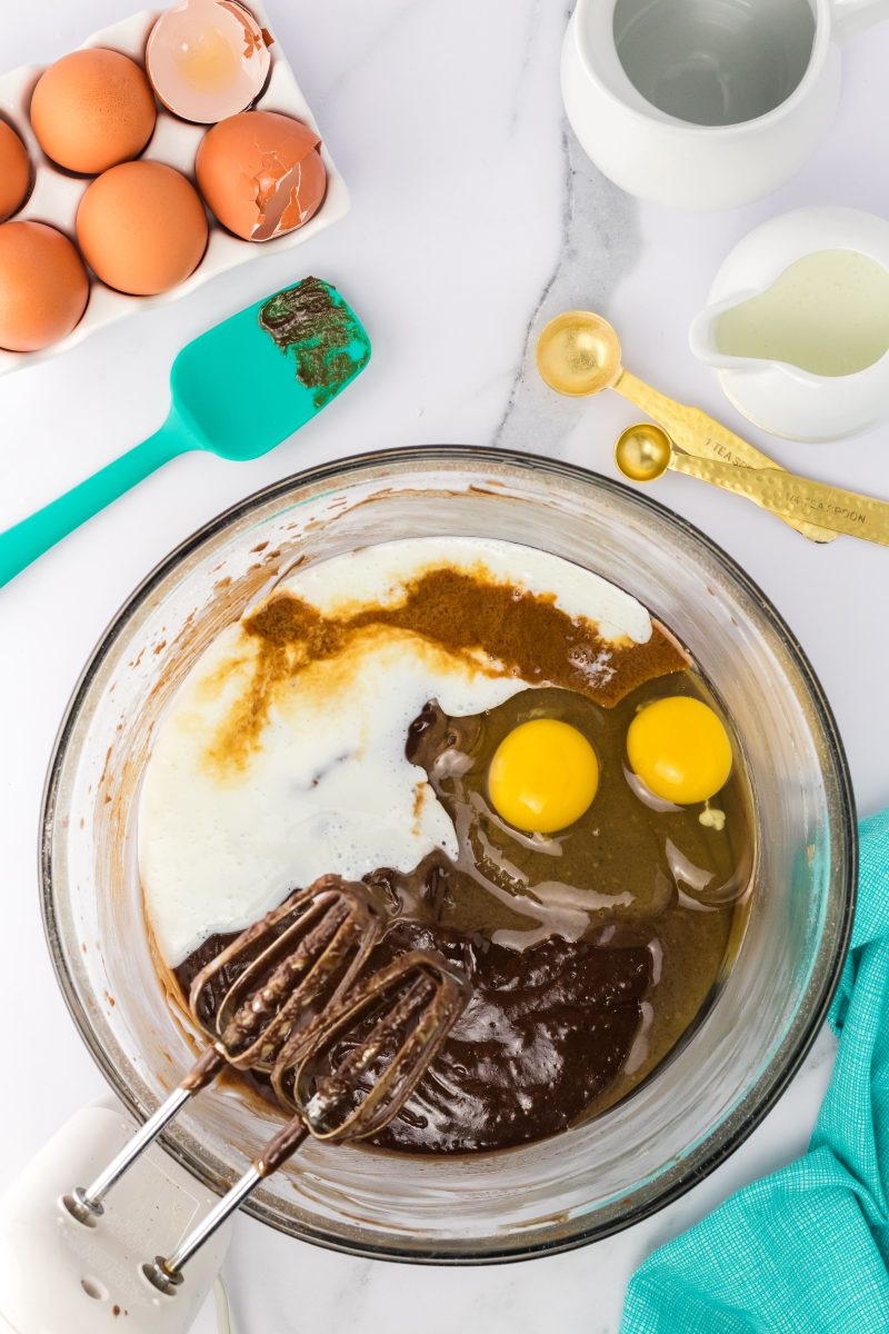 A mixing bowl filled with a chocolate mixture with eggs, vanilla, and buttermilk. Hostess At Heart