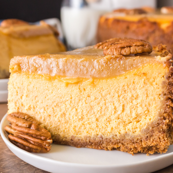 Tableview of a slice of cheesecake with a pumpkin filling sitting on a graham cracker crust and topped with praline. Hostess At Heart
