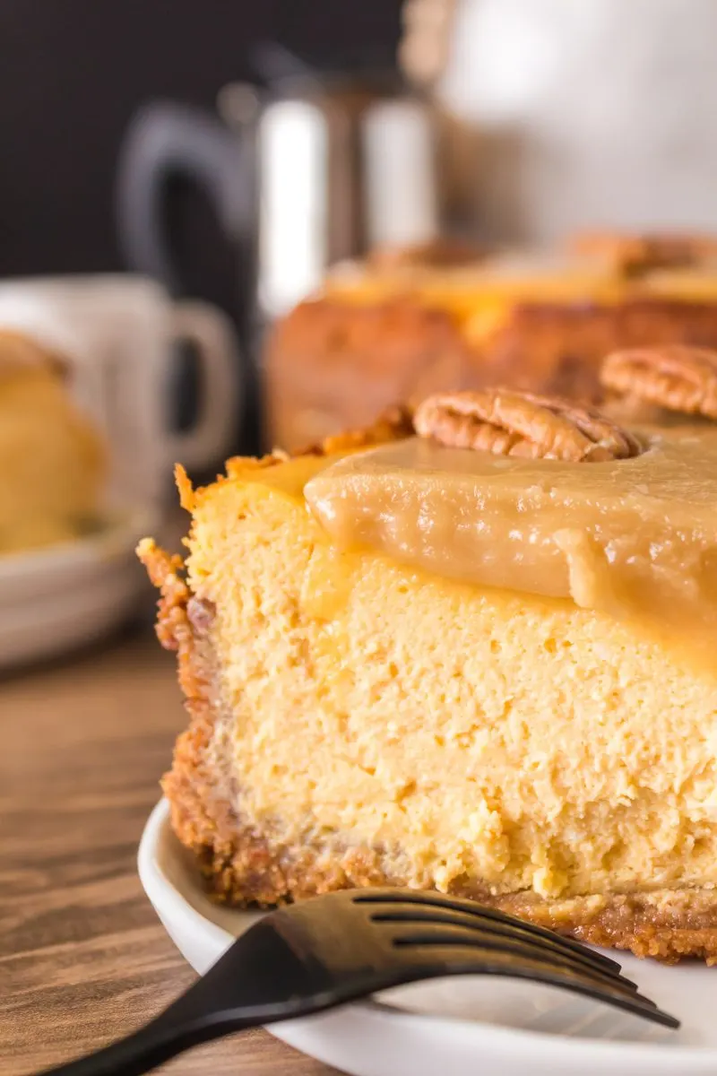 Closeup tableview shot of a slice of Pumpkin Pecan Cheesecake Pie showing creamy filling over a graham cracker crust - Hostess At Heart