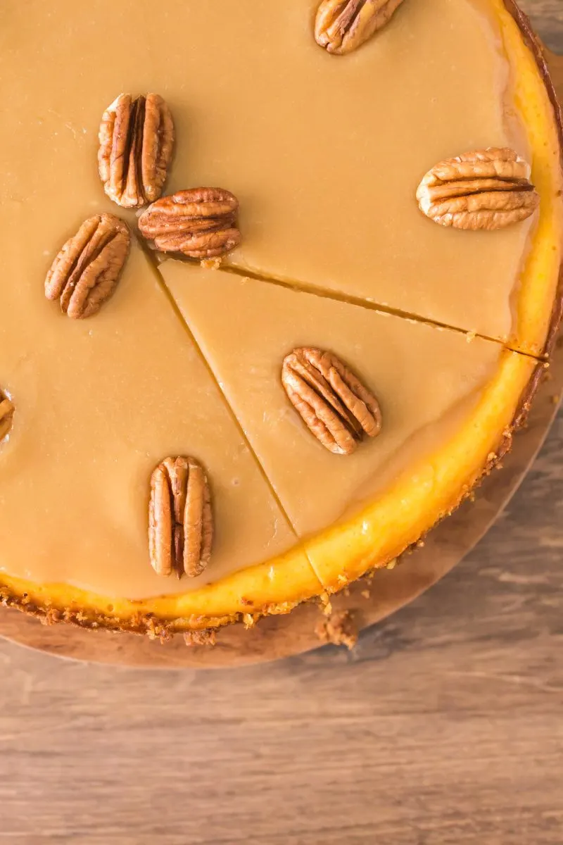 Top down view of a pumpkin cheesecake with the first cuts taking to remove the first slice. Hostess At Heart