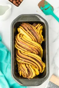 Top down view of pumpkin bread dough filled with Nutella that's been twisted as a Babka bread recipe in a loaf pan - Hostess At Heart