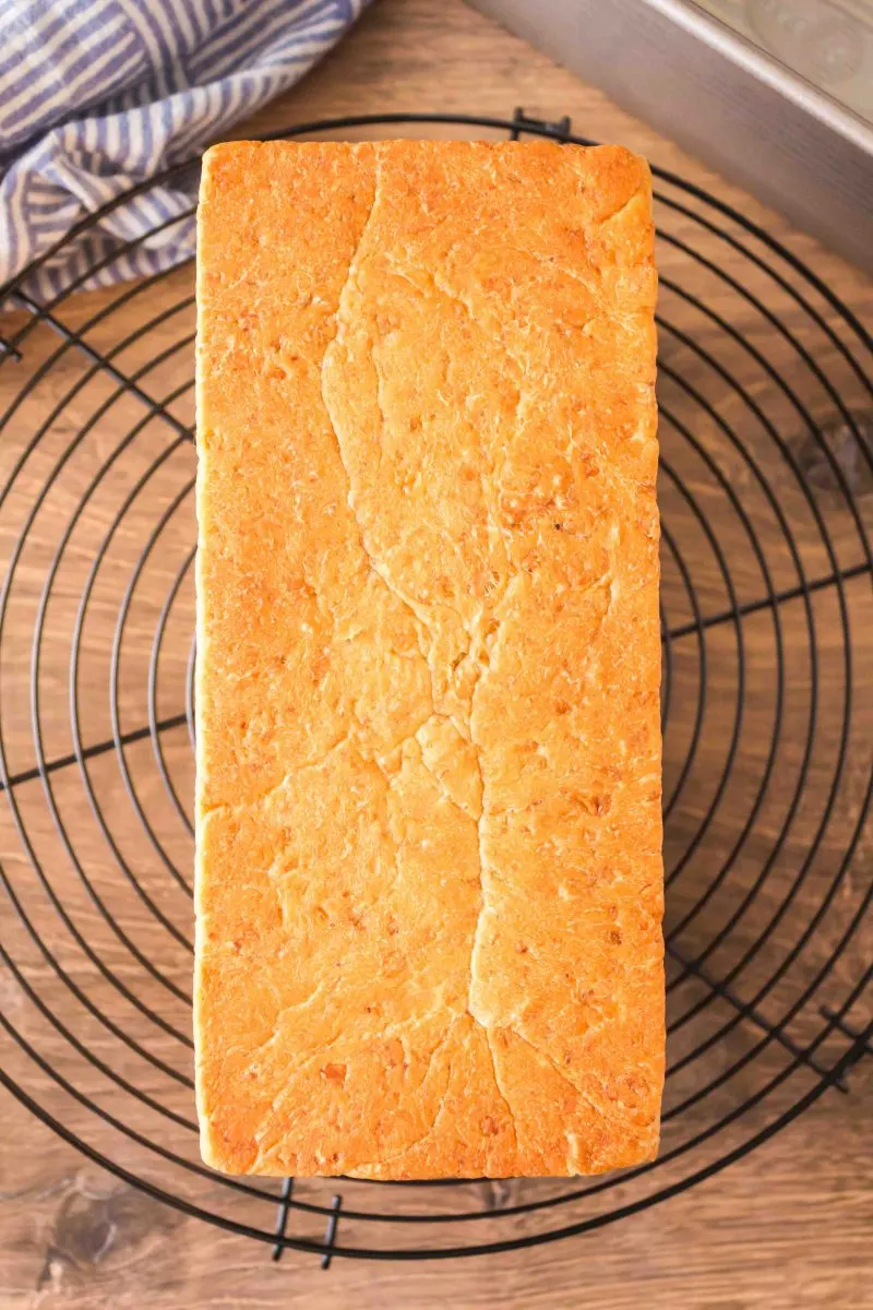 Loaf of baked pain de mie bread cooling on a wire rack.