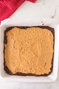 Top down view of a prepared pan filled with brownie batter topped with a layer of chunky peanut batter topping - Hostess At Heart
