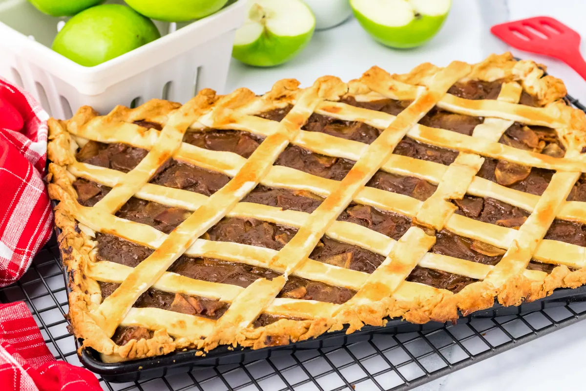 Angled view of a baked caramel apple pie in a sheet pan and topped with lattice. Hostess At Heart