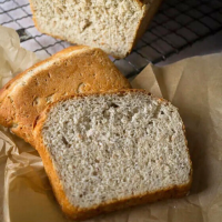 Angled view of a slice of wheat bread with the cut loaf in the rear. Hostess At Heart