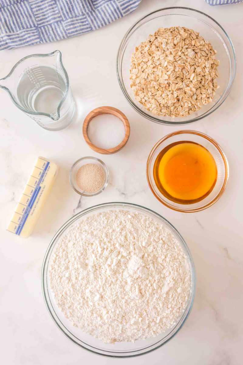 Ingredients used to bake Honey Oat Pain de Mie including flour, honey, yeast, water, salt, and butter.