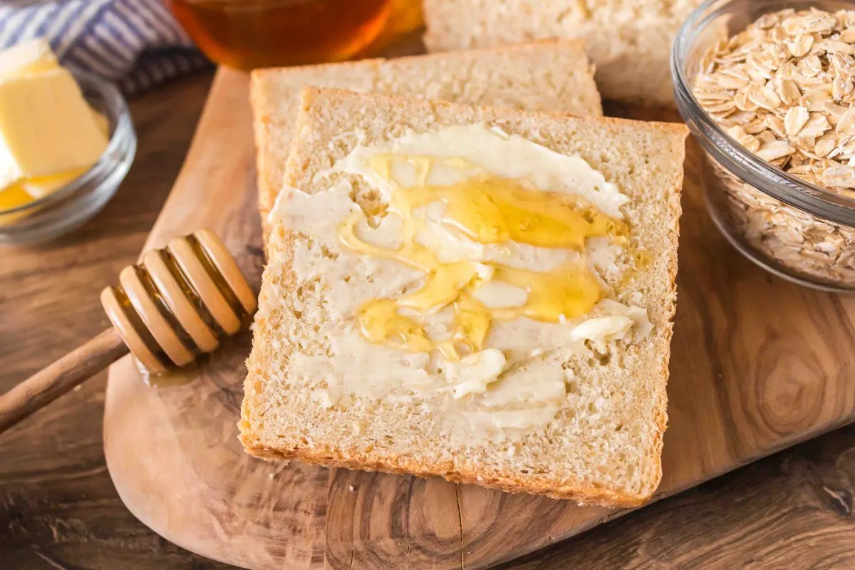 A slice of pain de mie bread topped with butter and honey.