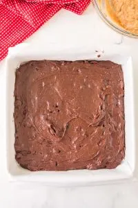 A parchment paper lined baking dish filled with brownie batter - Hostess At Heart