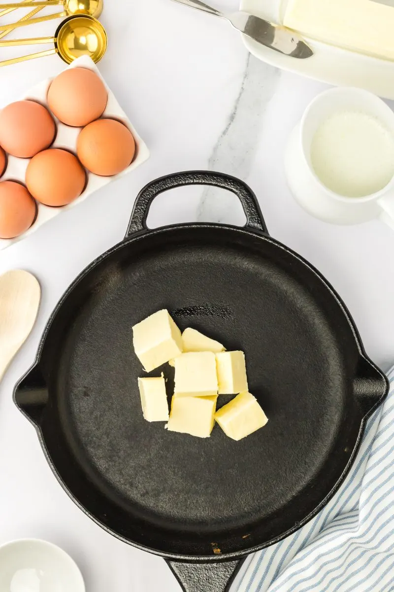 Top down view of cubes of butter sitting in a castiron skillet - Hostess At Heart