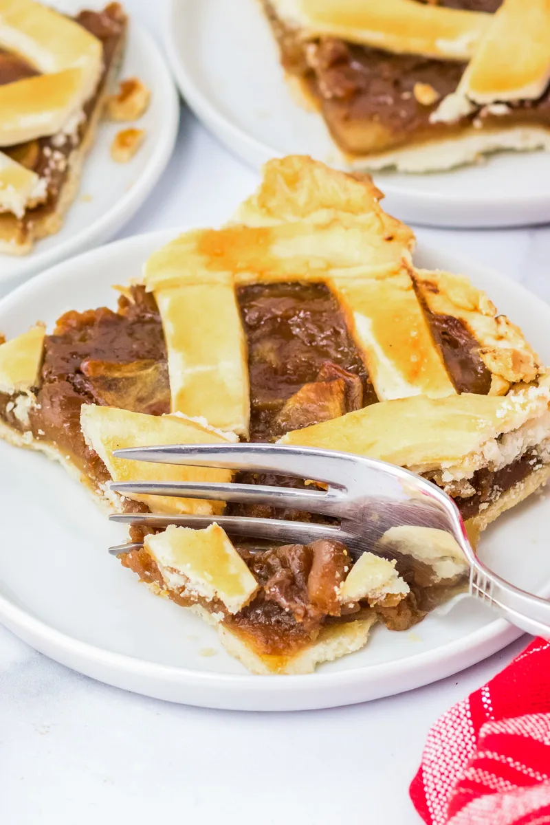 A square slice of an apple slab pie with a fork cutting the front piece - Hostess At Heart