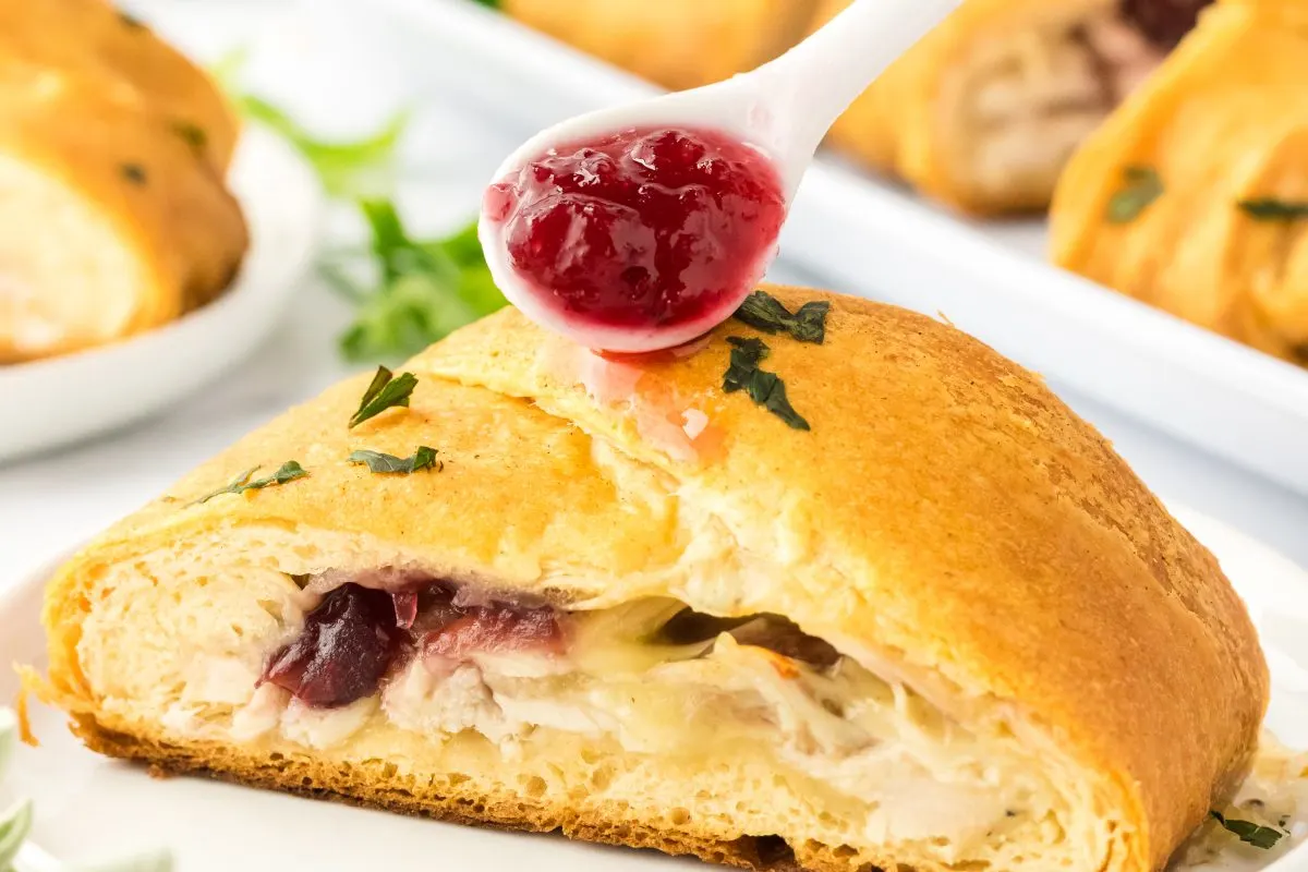 Cranberry sauce being spooned over a turkey braid - Hostess At Heart