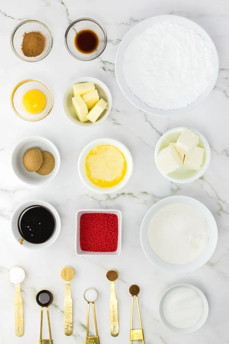 Top down view of ingredients: cinnamon, vanilla, egg yolk, butter, powdered sugar, ginger, brown sugar, molasses, all purpose flour, granulated sugar, baking soda, salt, nutmeg, and cloves.