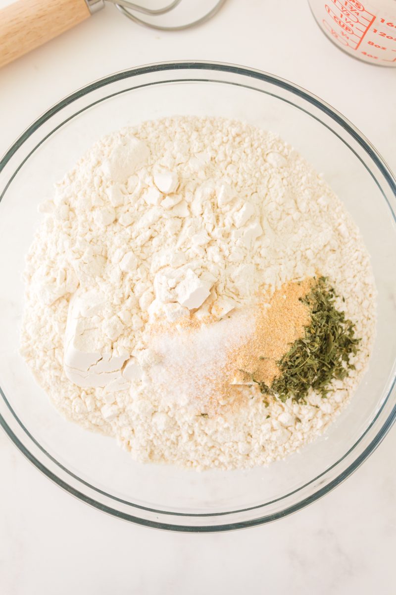 Combined dry ingredients used to make bread including flour, parsley, granulated garlic, and salt
