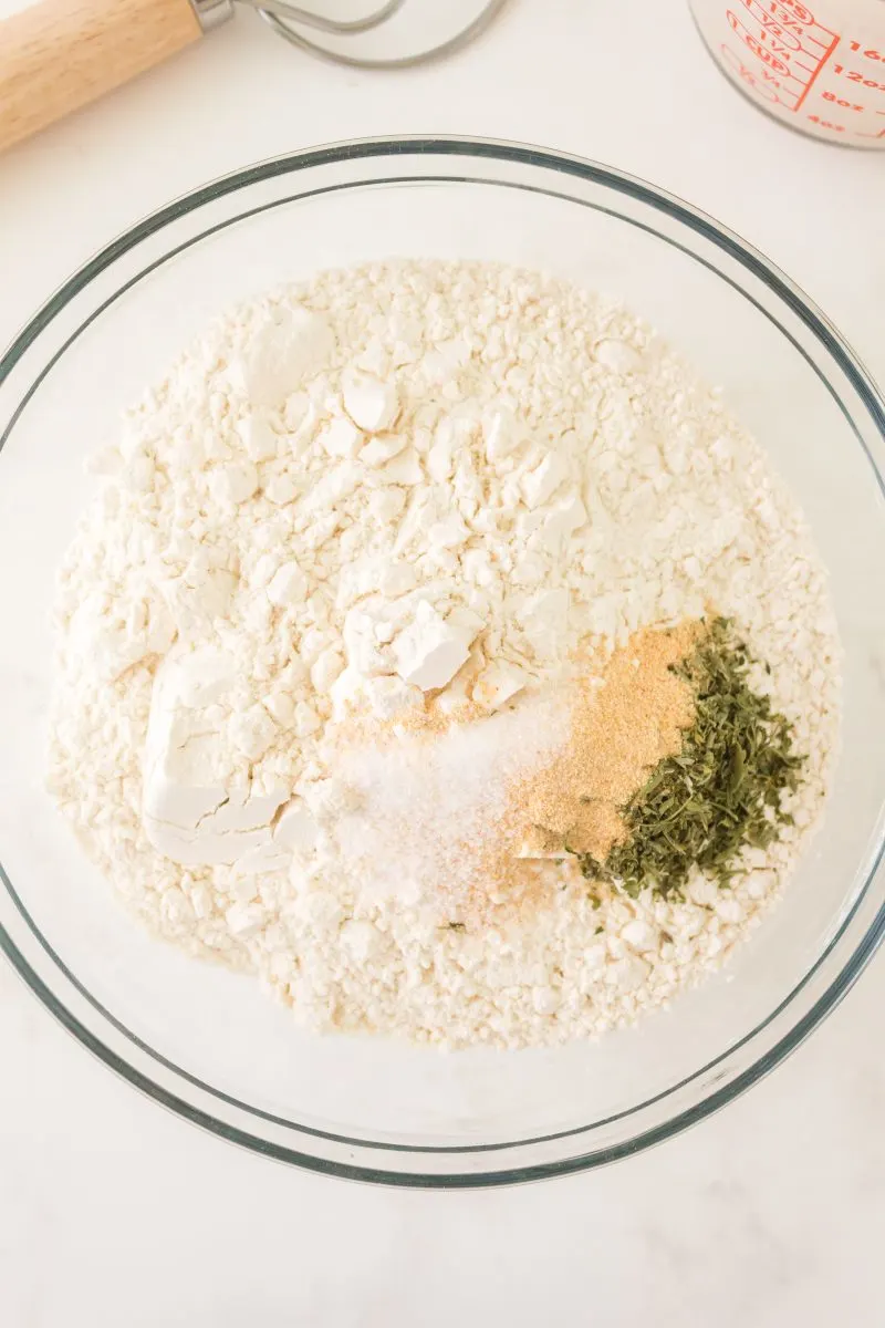 Combined dry ingredients used to make bread including flour, parsley, granulated garlic, and salt