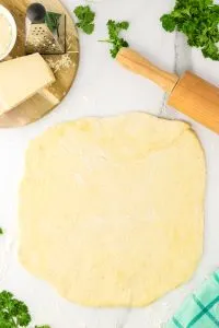 Pizza dough rolled out over a flour-dusted surface - Hostess At Heart