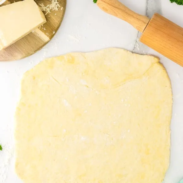 Pizza dough rolled out over a flour-dusted surface - Hostess At Heart