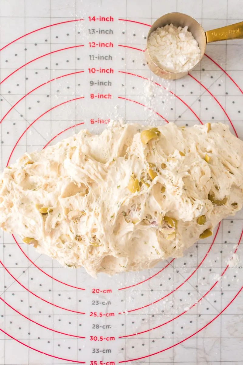 Sticky dough shaped into a loaf sitting on a measuring matt. Hostess At Heart