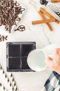 Water being added to a silicone ice cube mold in order to make chocolate cups - Hostess At Heart