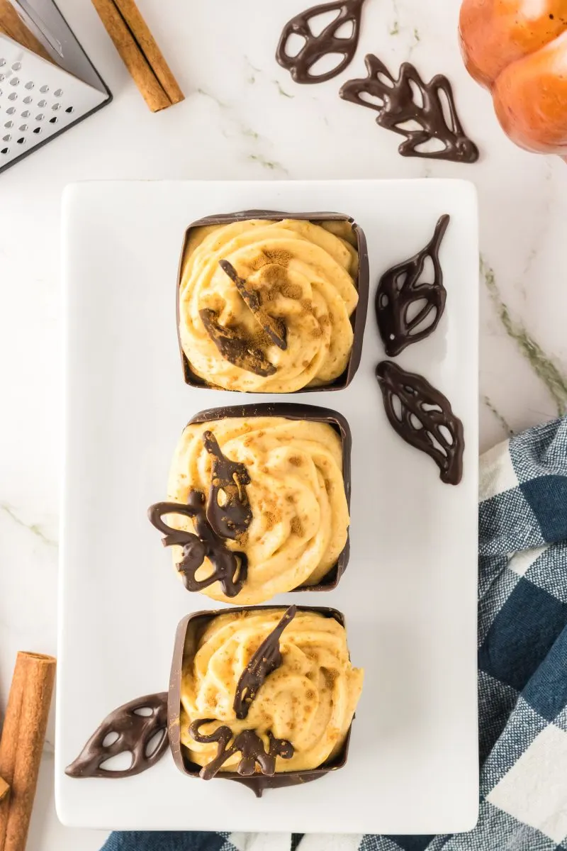 Top down view of homemade chocolate cups filled with pumpkin mousse filling and topped with a chocolate leaf - hostess at heart