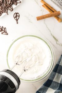 A bowl of whipped cream with soft peaks to make Pumpkin Chiffon Mousse - Hostess At Heart