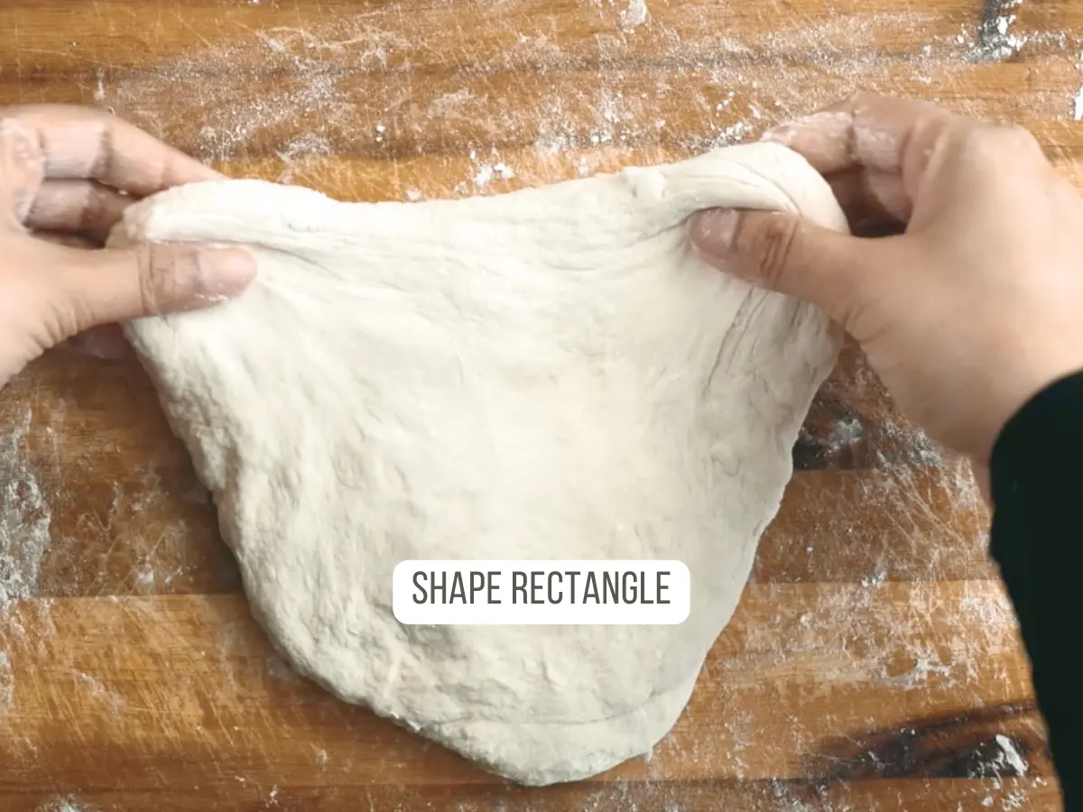 A piece of bread dough shaped into a rustic rectangle for shaping into a Batards Bread loaf - Hostess At Heart