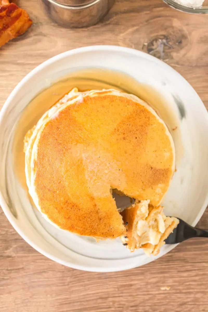 Top down view of a stack of sourdough pancakes with a fork lifting a bite - Hostess At Heart