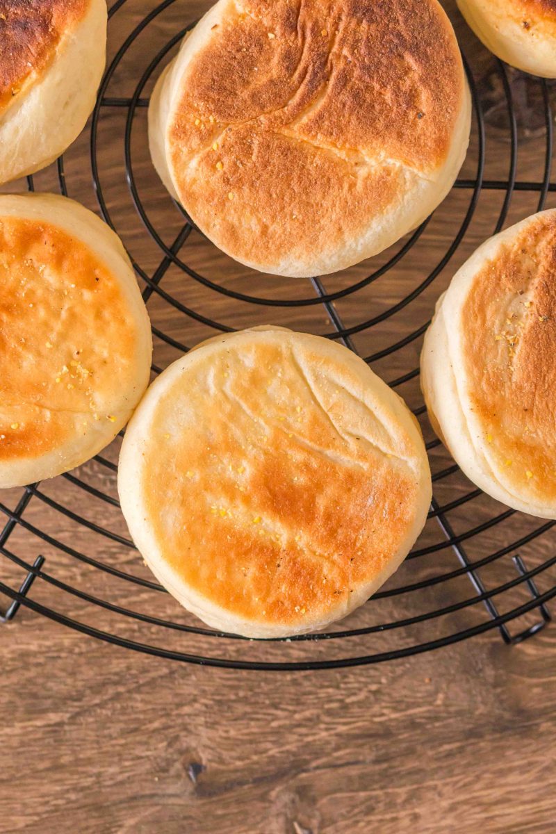 Top down view of golden brown English Muffins on a cooling rack. Hostess At Heart