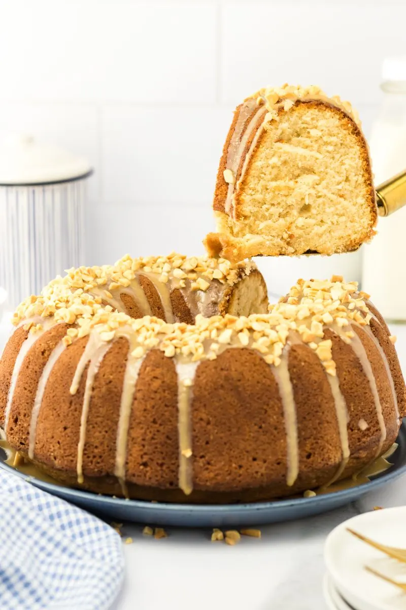 Sideview of a peanut butter cake slice hovering over the cut cake - Hostess At Heart