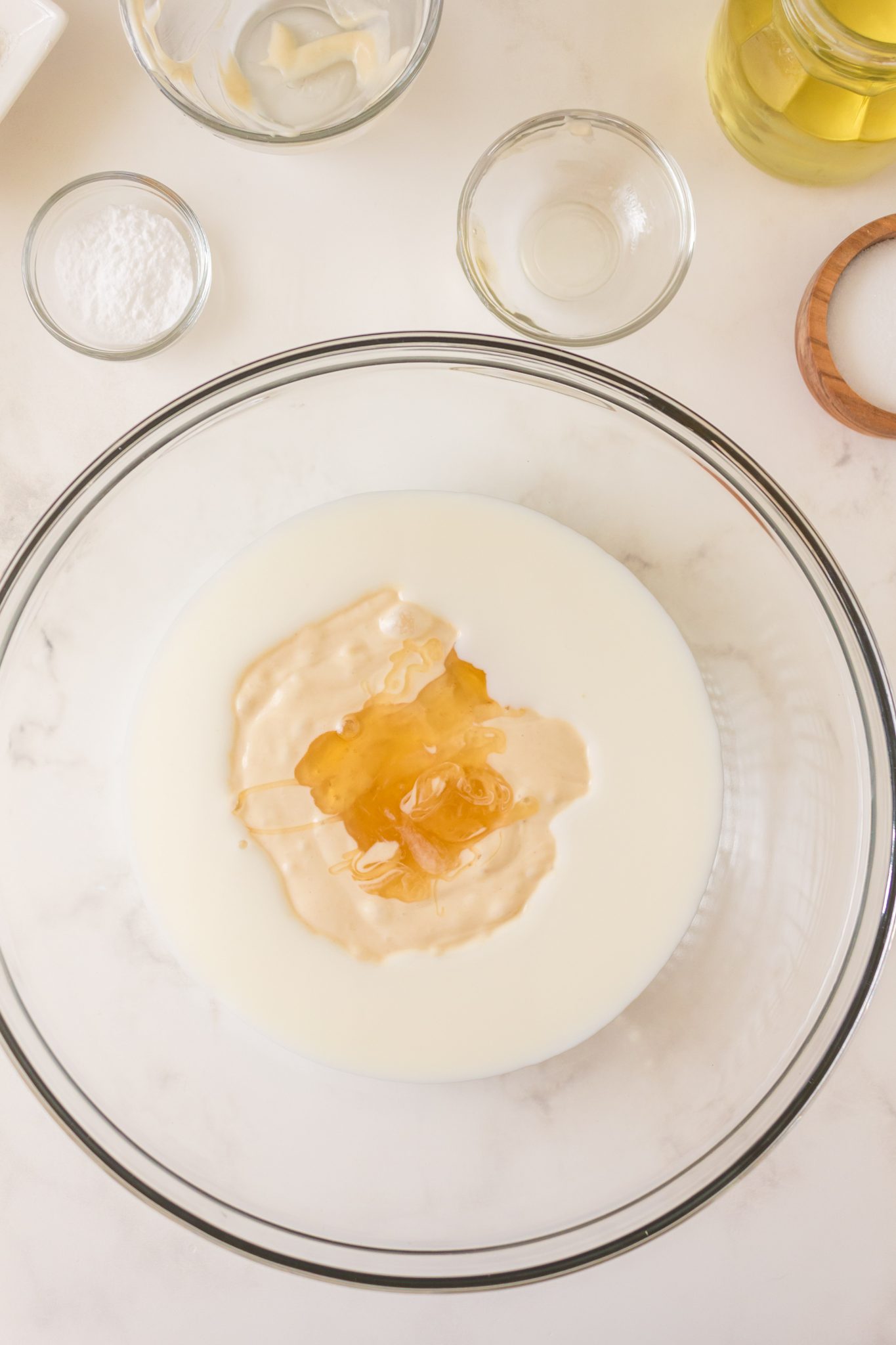 Wet ingredients combined in a mixing bowl for homemade sourdough discard pancakes including sourdough starter, honey, and milk. Hostess At Heart