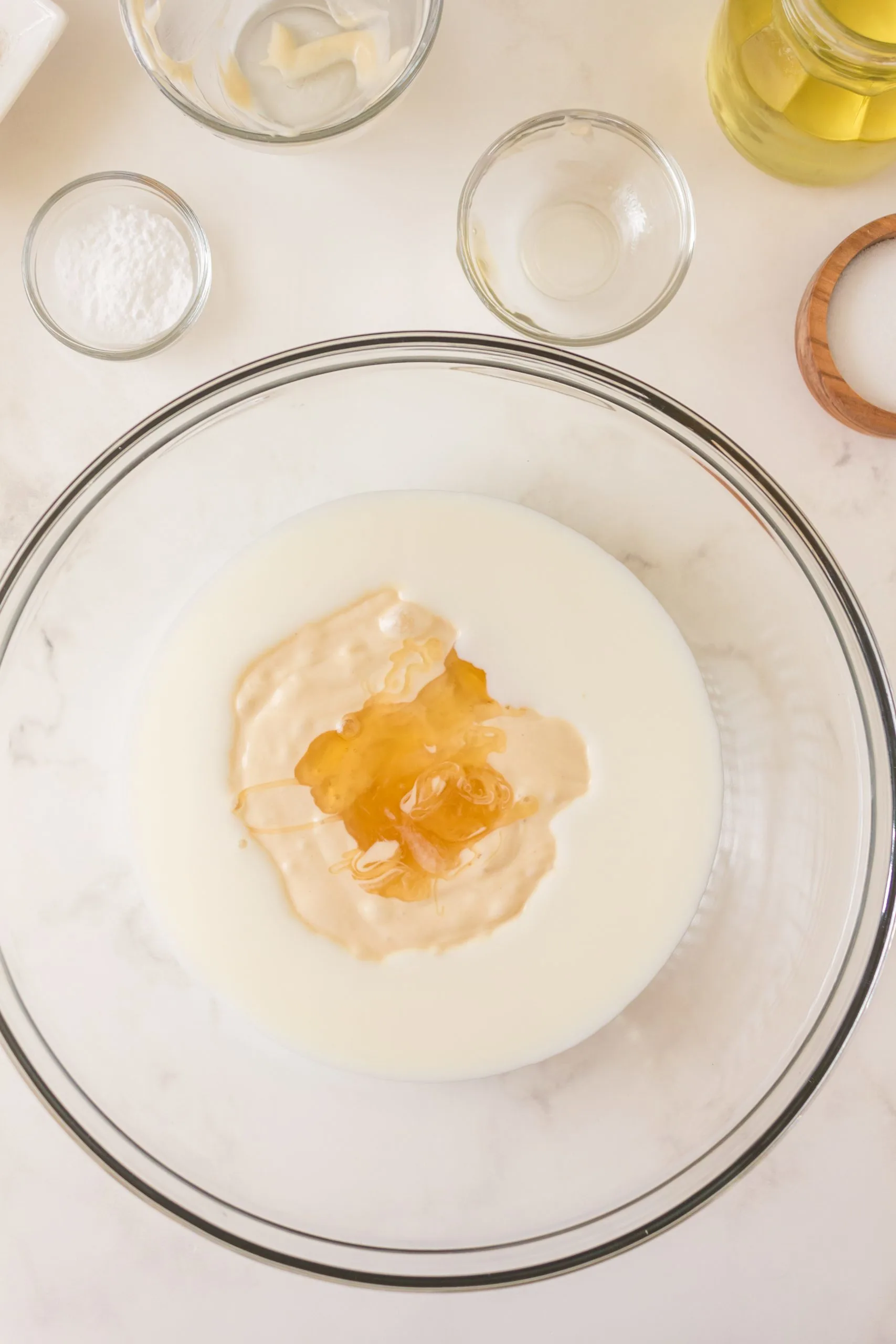 Wet ingredients combined in a mixing bowl for homemade sourdough discard pancakes including sourdough starter, honey, and milk. Hostess At Heart