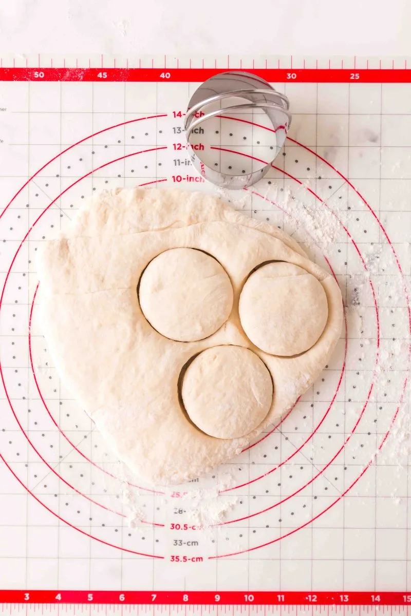 Top down view of English muffin dough being cut. - Hostess At Heart