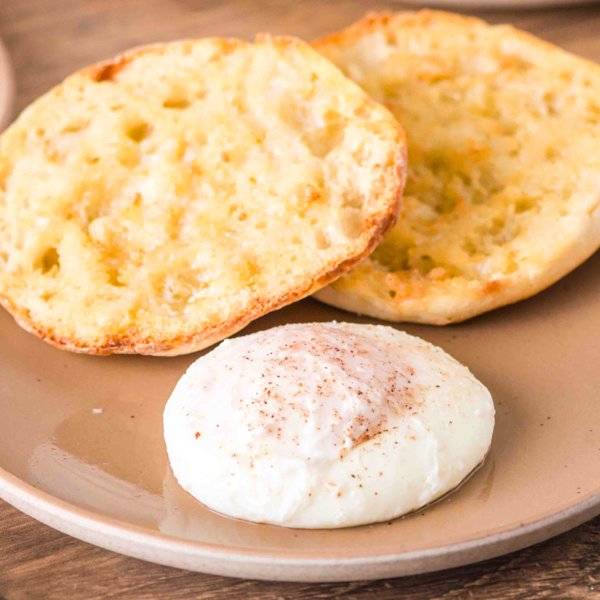 Front view of a perfectly poached egg on a plate in front of a toasted English Muffin - Hostess At Heart