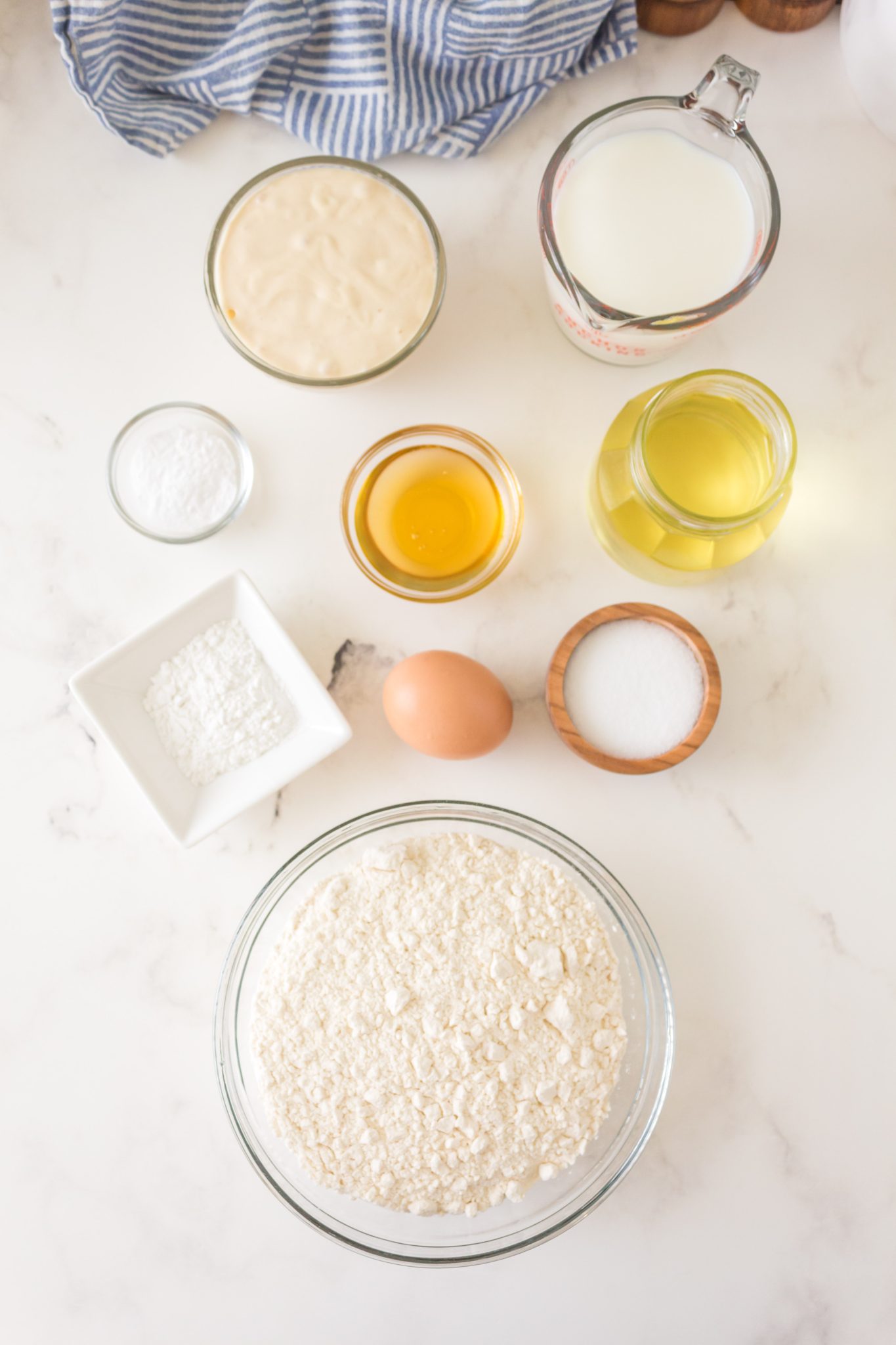 Ingredients used to make a Sourdough Pancakes recipe including sourdough starter, egg, salt, honey, oil, flour, baking powder and baking soda.