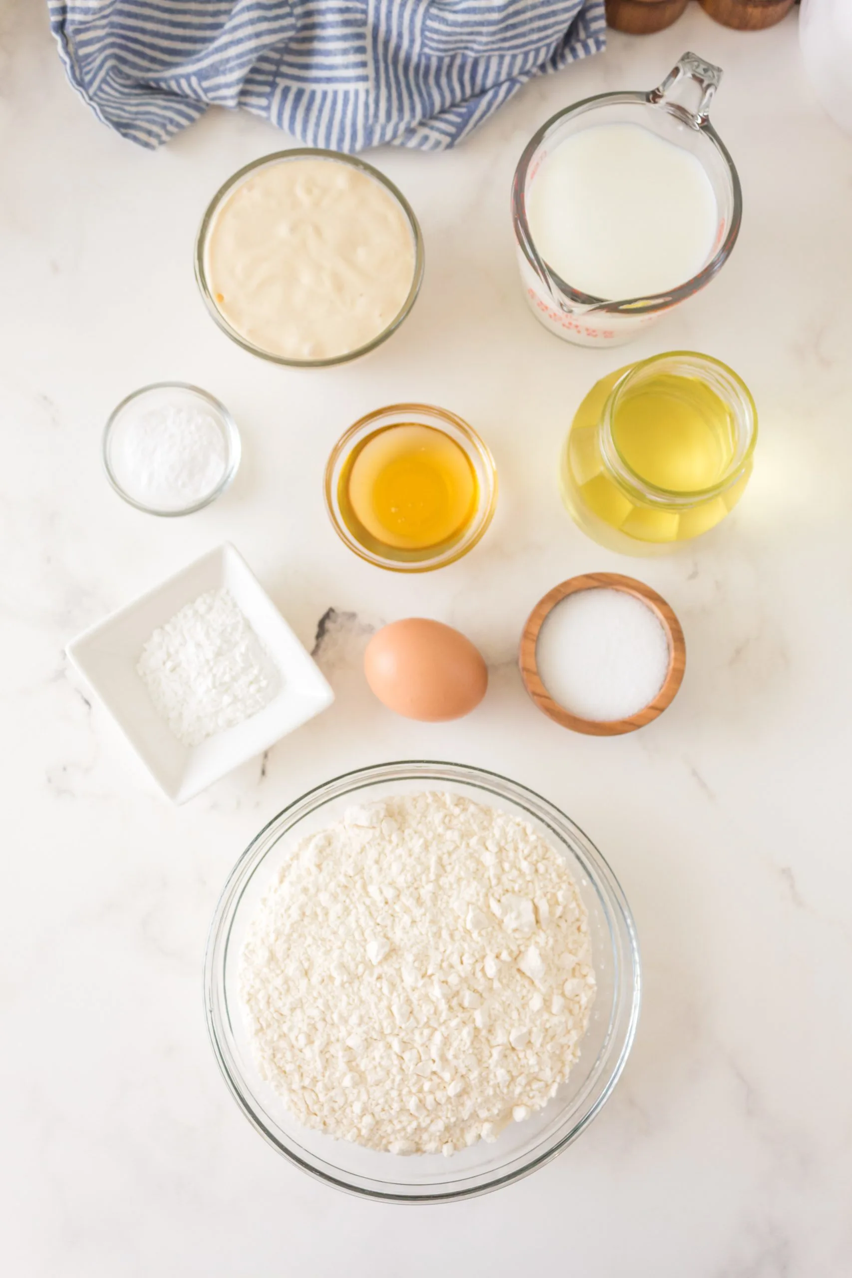 Ingredients used to make Sourdough Pancakes including sourdough starter, egg, salt, honey, oil, flour, baking powder and baking soda.