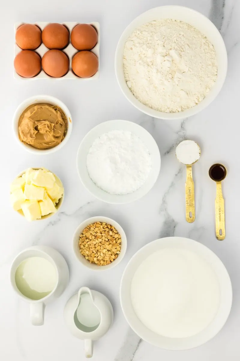 Ingredients used to make a peanut butter cake including buttermilk, sugar, peanut butter, flour, chopped peanuts, butter, eggs, baking powder, and water. Hostess At Heart