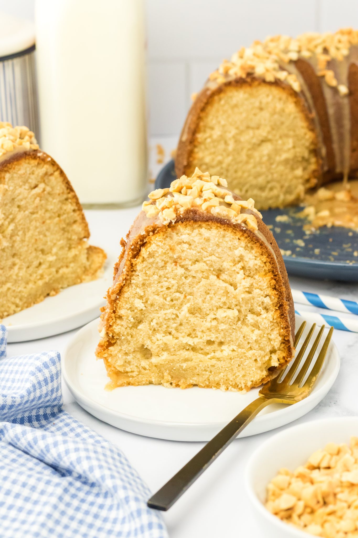 Side view of a slice of Glazed Peanut Butter Cake topped with chopped peanuts - Hostess At Heart