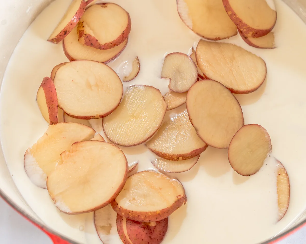Sliced red potatoes added to cream in a Dutch oven. Hostess At Heart
