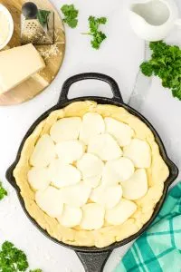 Cast Iron skilled lined with Pizza dough layered with slices of mozzarella cheese. Hostess At Heart