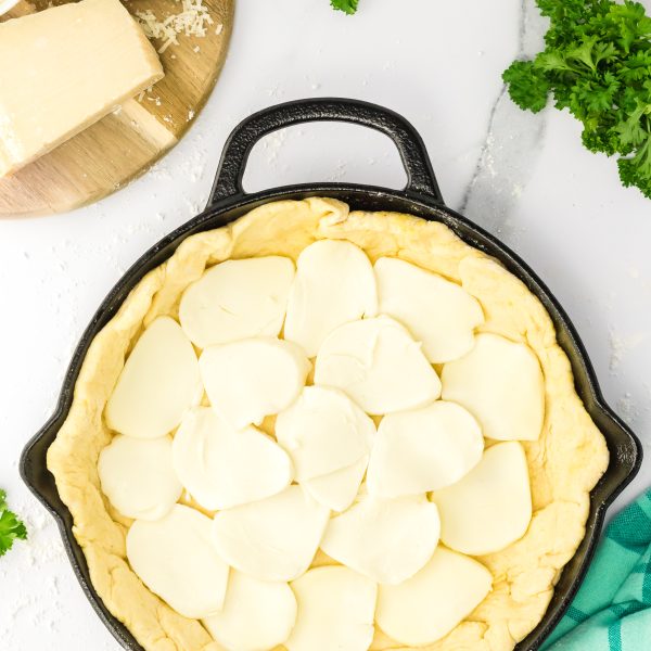 Cast Iron skilled lined with Pizza dough layered with slices of mozzarella cheese. Hostess At Heart