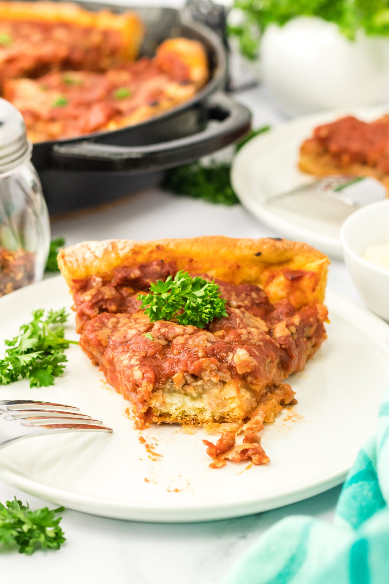 A slice of pizza on a plate with the front already eaten showing the thick layers. Hostess At Heart