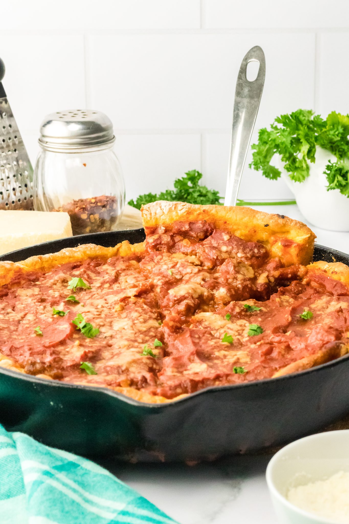 A slice of thick deep-dish pizza being lifted from the pan. - Hostess At Heart