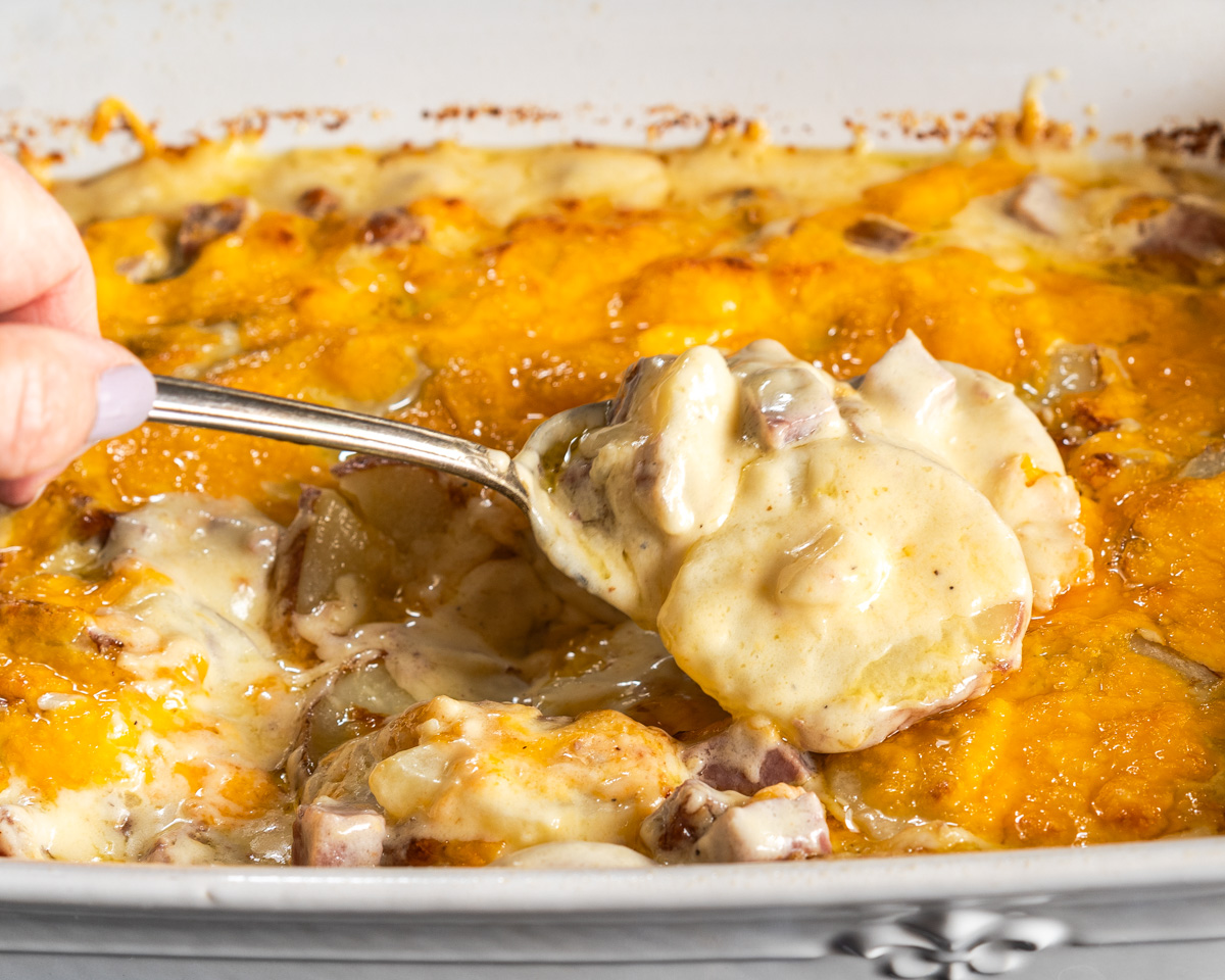 A spoonful of this Corned Beef Au Gratin Recipe lifted out of the pan for a close-up shot. Hostess At Heart