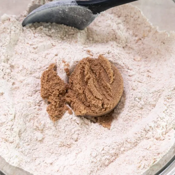 Brown sugar added to a bowl of whole wheat and all-purpose flour.