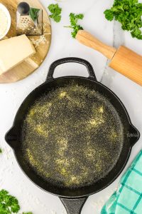 Top down view of a cast-iron skillet dusted with cornmeal. Hostess At Heart