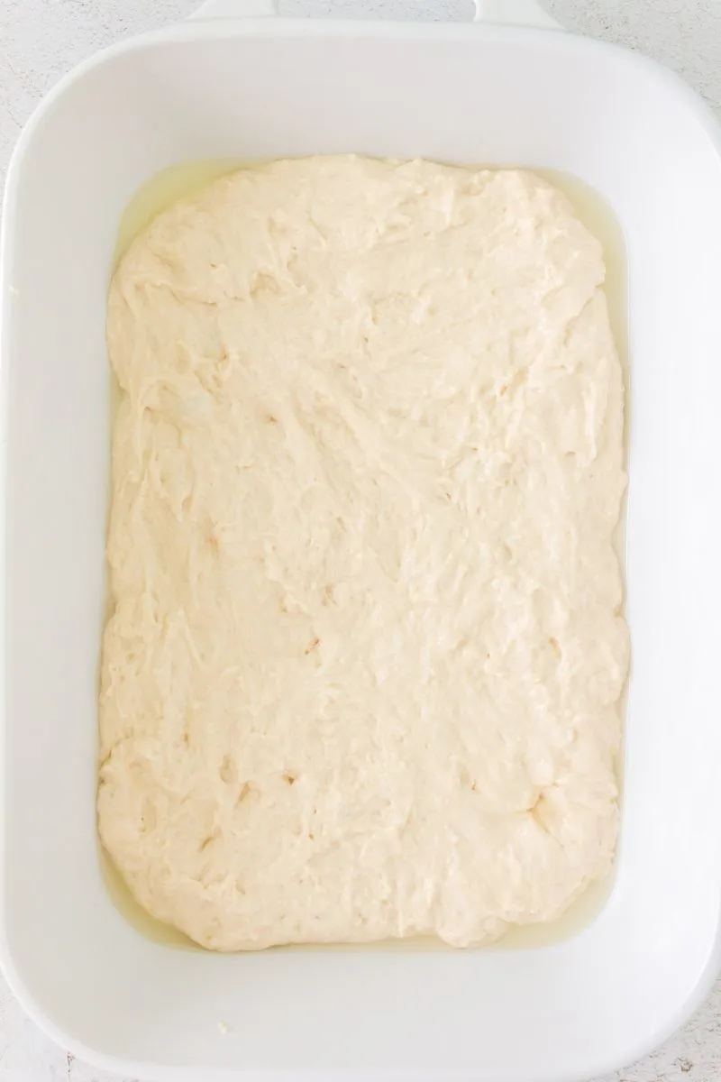 Stretched sour dough foccacia bread covering the bottom of a baking dish - Hostess At Heart